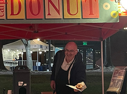 A man joyfully holds a donut, savoring its deliciousness with a smile on his face.